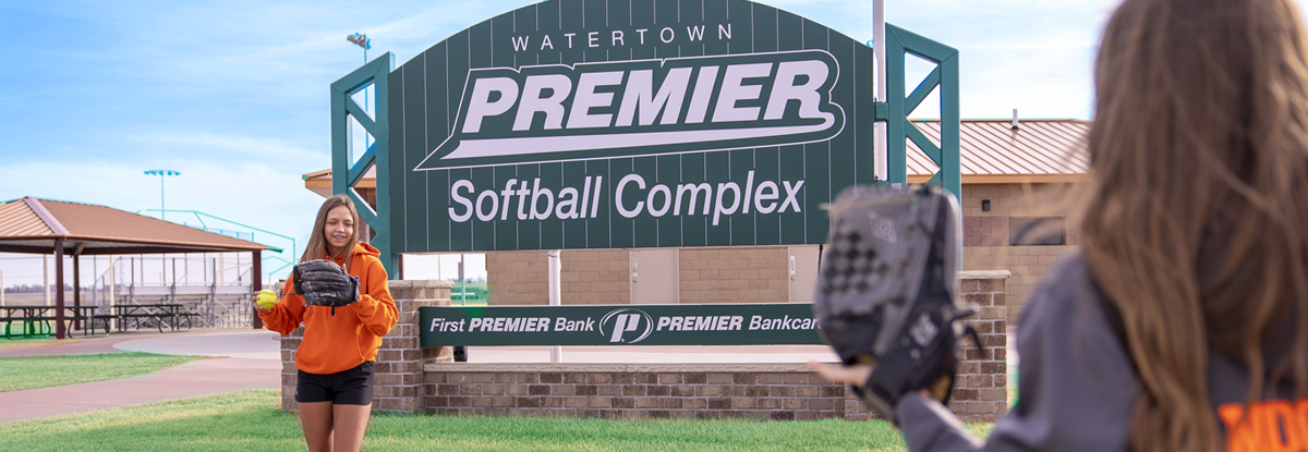 girls playing catch outside of softball complex