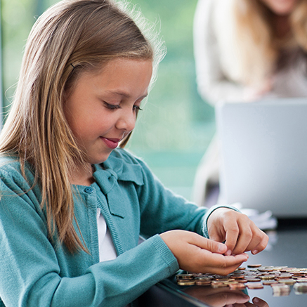 child putting coins in piggy bank