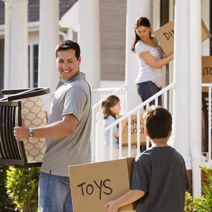 Family carrying boxes into new home.